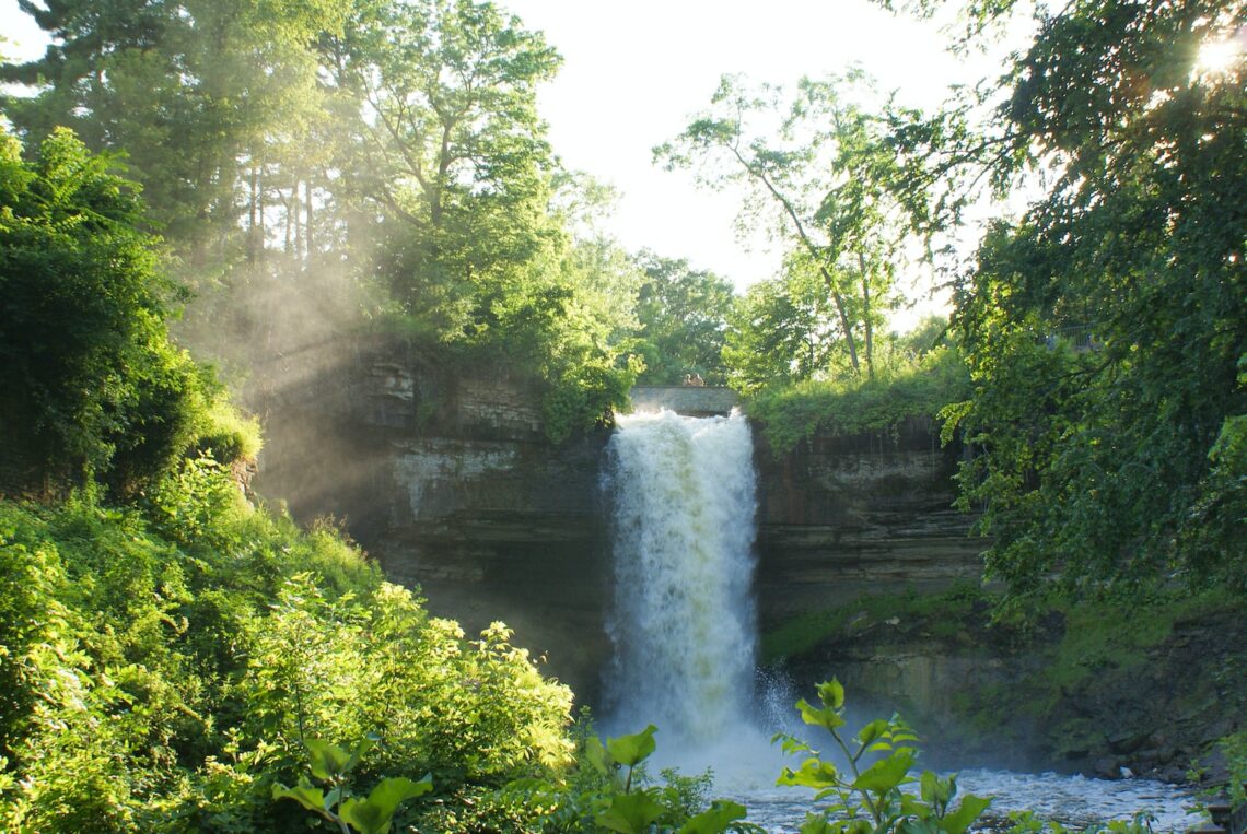 waterfalls surrounded by green trees during daytime