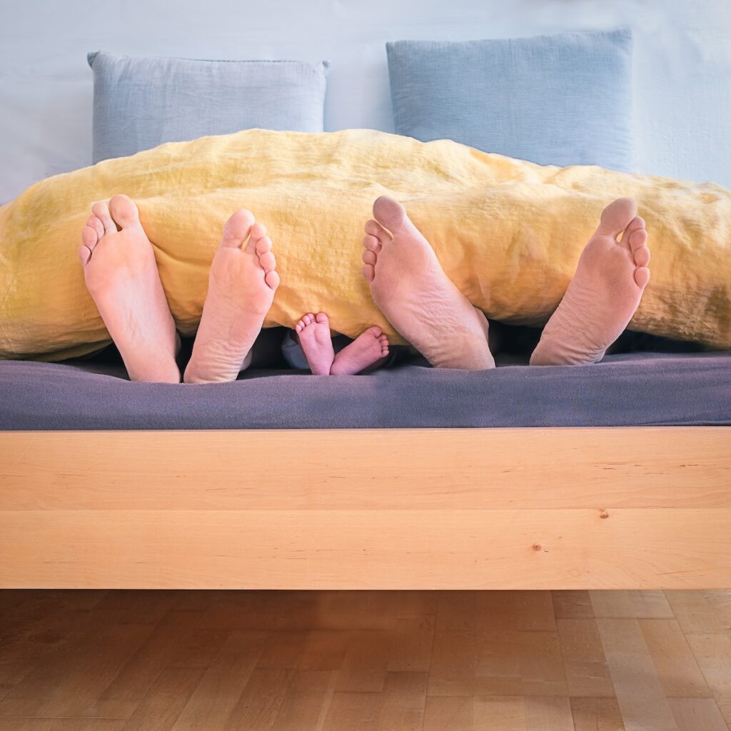 trois personnes sous un lit avec les pieds qui dépassent