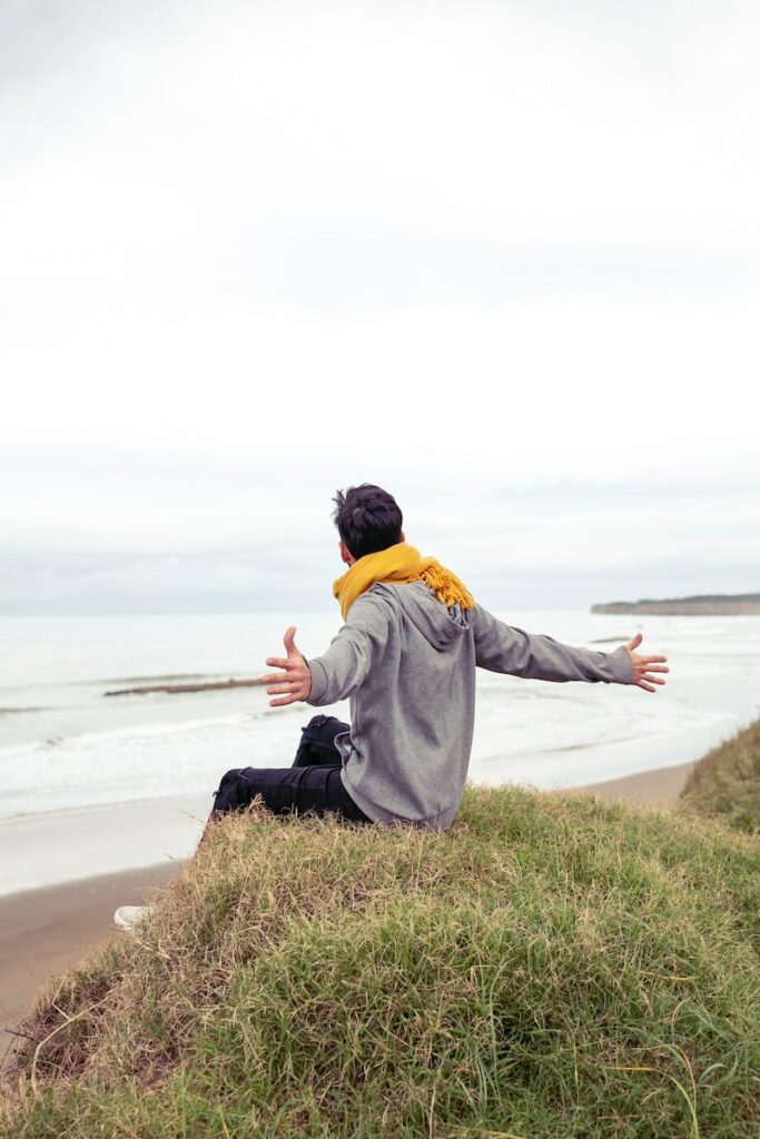 homme assis sur un rocher devant la mer