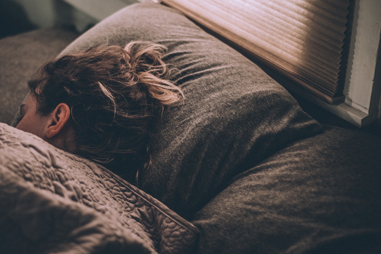 femme qui dort dans son lit sous ses draps