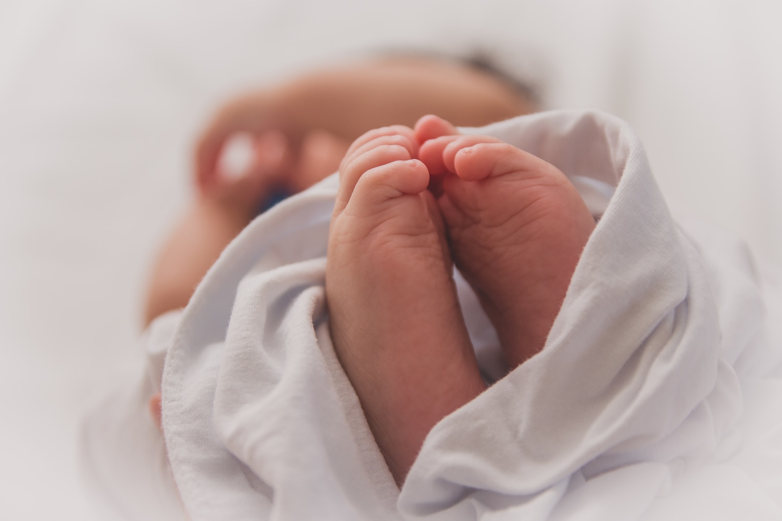 baby covered with white blanket doula