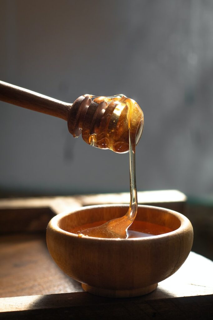 a honey dip being poured into a wooden bowl