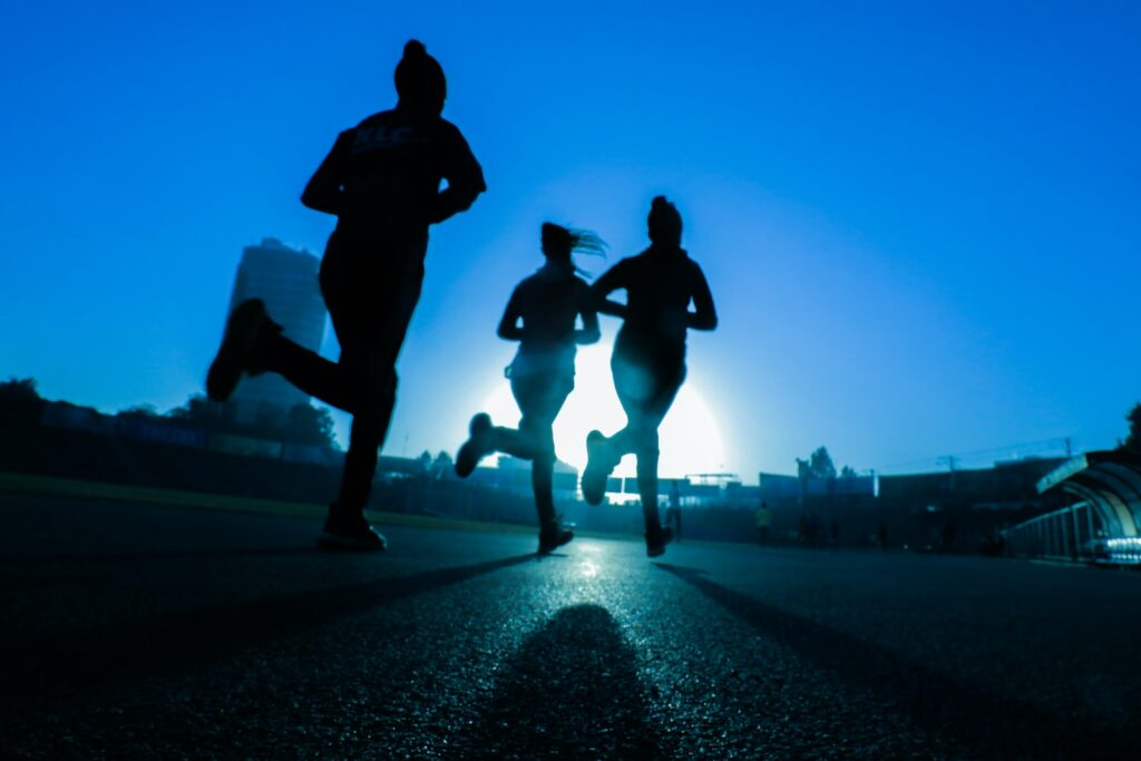 silhouette of three women running on grey concrete road activité sportive