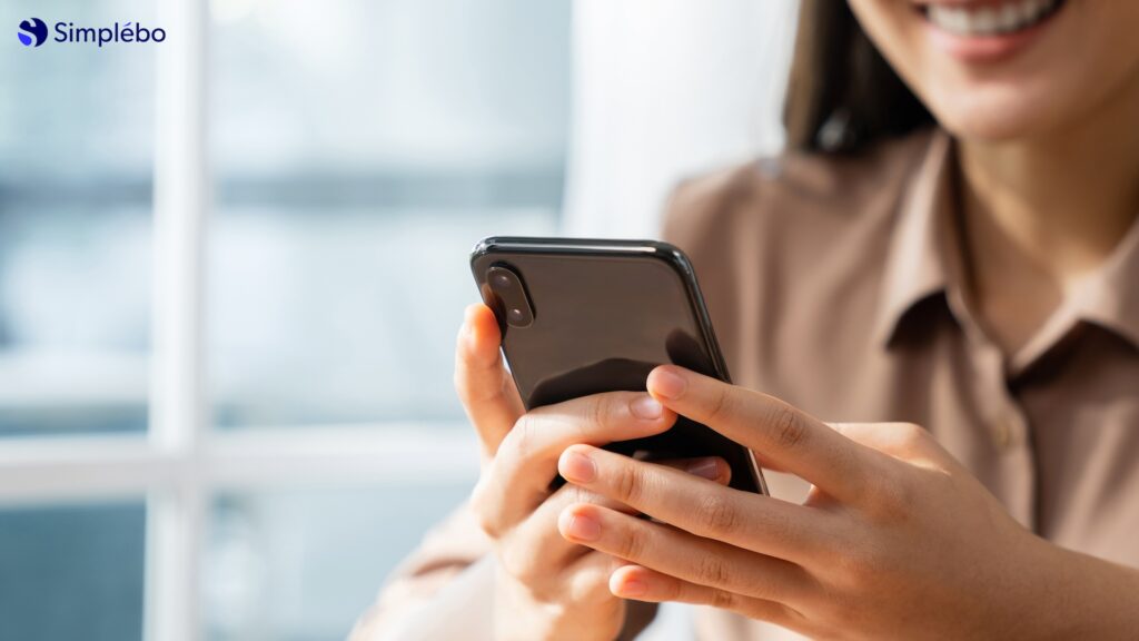 Une femme communique sur son smartphone pour développer son activité de praticienne en ligne